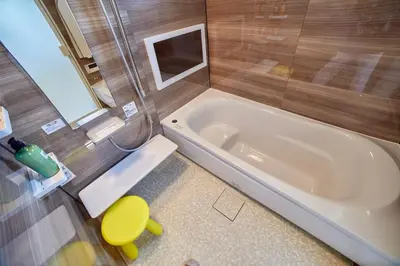 a bathroom with a tub and a yellow stool at Shinjuku 'Orange County' Villa in Tokyo