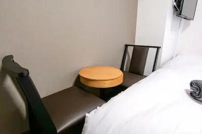 a small table and chair next to a bed at J-Court Oshiage in Tokyo