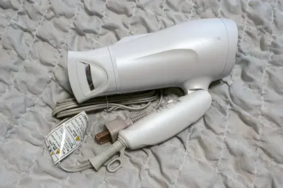 a hair dryer and a hair brush on a bed at J-Court Oshiage in Tokyo