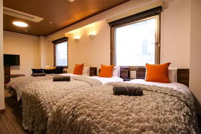 two beds in a room with orange pillows at J-Court Oshiage in Tokyo
