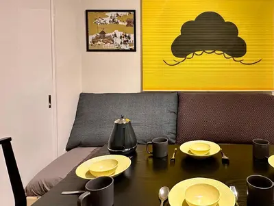 a table with plates on it in a room with a yellow wall at 山手線池袋駅 徒歩6分 東池袋駅徒歩3分 2~5人 エレベーター WIFI 新宿/渋谷/銀座/築地/浅草/原宿近い！ in Tokyo