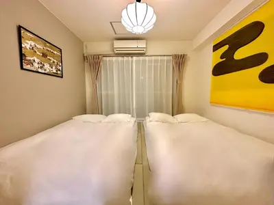 two large beds in a room with a window at 山手線池袋駅 徒歩6分 東池袋駅徒歩3分 2~5人 エレベーター WIFI 新宿/渋谷/銀座/築地/浅草/原宿近い！ in Tokyo