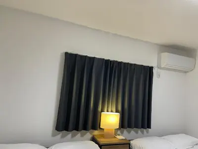a room with two beds and a window with a lamp at Private Hotel Season Spring in Tokyo