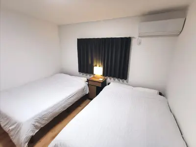 two beds in a small room with a lamp on a table at Private Hotel Season Spring in Tokyo