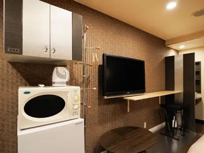 a kitchen with a microwave and a tv on a wall at 1st STEP HOTEL \u30d5\u30a1\u30fc\u30b9\u30c8\u30b9\u30c6\u30c3\u30d5\u309a\u30db\u30c6\u30eb in Tokyo