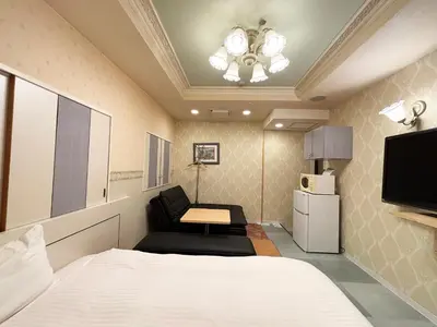 a bedroom with a bed and a couch and a tv at 1st STEP HOTEL \u30d5\u30a1\u30fc\u30b9\u30c8\u30b9\u30c6\u30c3\u30d5\u309a\u30db\u30c6\u30eb in Tokyo