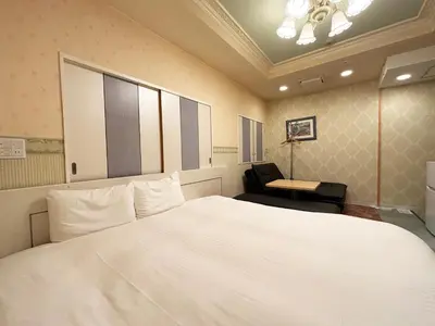 a bedroom with a large white bed and a chair at 1st STEP HOTEL \u30d5\u30a1\u30fc\u30b9\u30c8\u30b9\u30c6\u30c3\u30d5\u309a\u30db\u30c6\u30eb in Tokyo