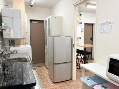 a kitchen with a refrigerator and a table in it at 1st STEP HOTEL \u30d5\u30a1\u30fc\u30b9\u30c8\u30b9\u30c6\u30c3\u30d5\u309a\u30db\u30c6\u30eb in Tokyo