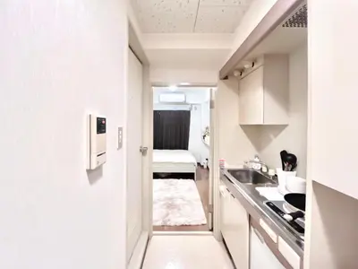 a small white kitchen with a sink and a bed at Ikebukuro Sugamo 202 in Tokyo