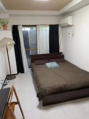 a bedroom with a bed and a lamp and a window at Wise Park Mukojima in Tokyo