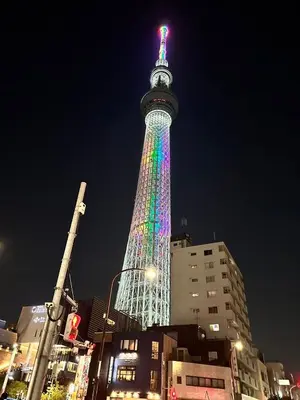 a tall tower lit up in rainbow colors at night at Wise Park Mukojima in Tokyo