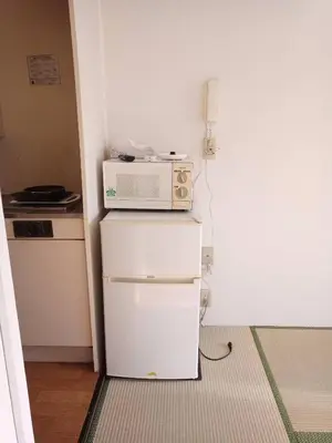 a small kitchen with a microwave on top of a refrigerator at Wise Park Mukojima in Tokyo