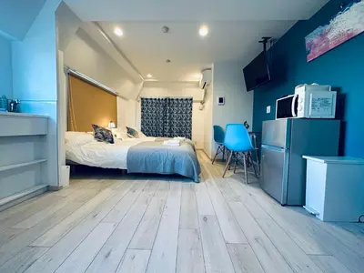 a bedroom with blue walls and a bed and a microwave at Hotel COMACHI in Tokyo