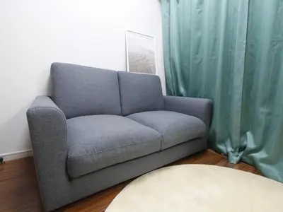 a gray couch in a living room with green curtains at Duo Scala Shinjuku \u6771\u65b0\u5bbf in Tokyo