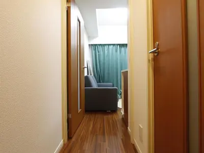 a hallway leading to a room with a blue chair at Duo Scala Shinjuku \u6771\u65b0\u5bbf in Tokyo