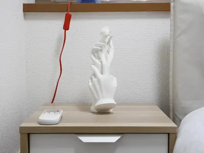 a white hand statue on a nightstand next to a remote control at Duo Scala Shinjuku \u6771\u65b0\u5bbf in Tokyo