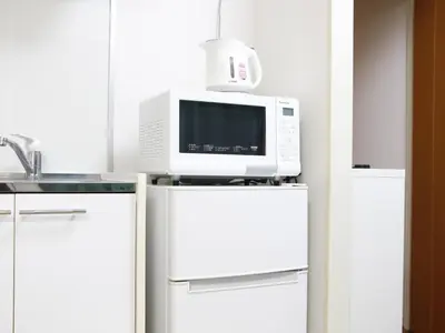 a microwave on top of a refrigerator in a kitchen at Duo Scala Shinjuku \u6771\u65b0\u5bbf in Tokyo