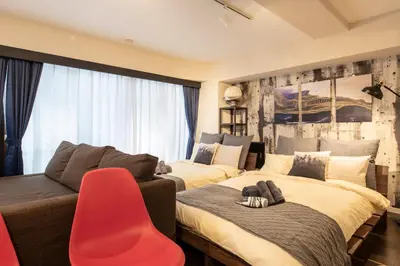 a bedroom with two beds and a red chair at \u30ea\u30ce\u30b9\u30bf\u30a4\u30eb\u62bc\u4e0a in Tokyo