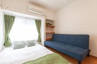 a bedroom with a blue couch and a window at \u8981\u753a \u4e00\u6238\u5efa\u8cb8\u5bb6 in Tokyo