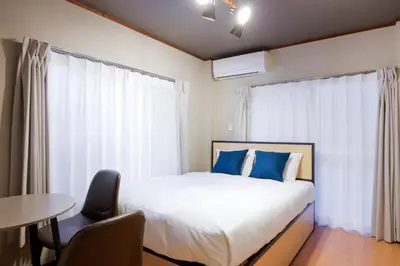 a bedroom with a bed with blue pillows and a table at \u30d1\u30eb\u30b3\u30fc\u30c8\u6c60\u888b in Tokyo