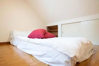 a bed with white sheets and a red pillow at \u30d1\u30f3\u30b7\u30aa\u30f3\u62bc\u4e0a in Tokyo