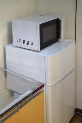 a microwave sitting on top of a refrigerator at \u6e0b\u8c37\u672c\u753a4\u4e01\u76ee\u6238\u5efa in Tokyo