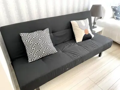 a black couch with pillows in a living room at COMMA HOUSE Nishi-ikebukuro 2223 in Tokyo