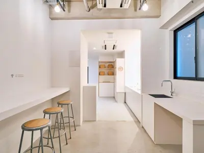 a kitchen with white counters and stools and a window at Hotel Plus Hostel TOKYO ASAKUSA 1 in Tokyo