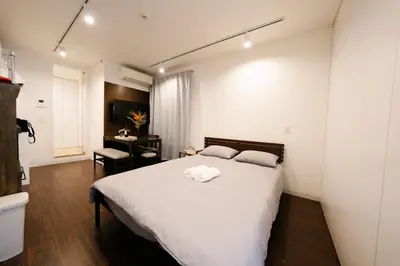 a bedroom with a large white bed and a desk at FL Residence Shinjuku Kawadacho in Tokyo