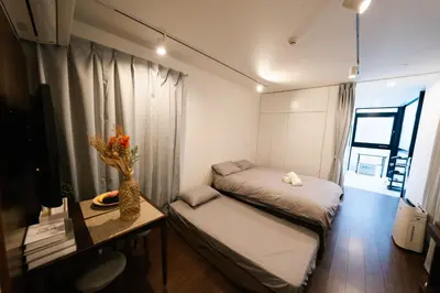 a small room with two beds and a desk with a table at FL Residence Shinjuku Kawadacho in Tokyo