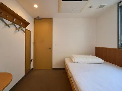 a small room with a bed and a door at Hotel Plus Hostel TOKYO ASAKUSA 2 in Tokyo