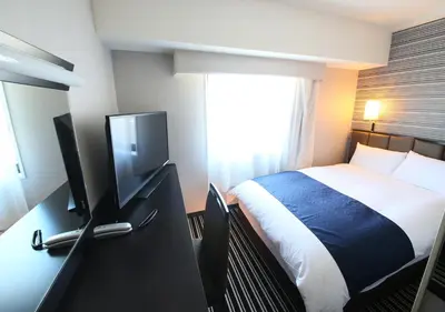 a bedroom with a bed and a desk with a television at APA Hotel Shinjuku Gyoemmae in Tokyo