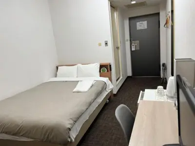a bedroom with a bed and a table and a door at Hotel Royal Oak Gotanda in Tokyo
