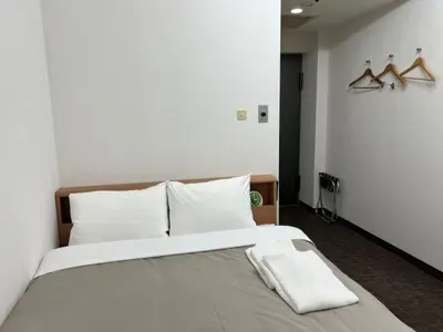 a bedroom with a large bed with white sheets and hangers at Hotel Royal Oak Gotanda in Tokyo