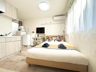 a bedroom with a large bed and a kitchen at nestay apartment tokyo waseda in Tokyo