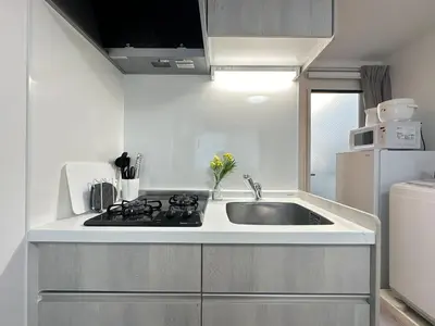 a white kitchen with a sink and a refrigerator at nestay apartment tokyo waseda in Tokyo