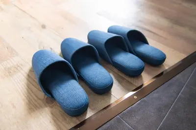 a row of blue rubber shoes on a wooden floor at Yoyogi Apartment 1-401 by Tranova in Tokyo