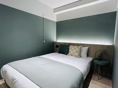 a bedroom with a white bed with a green wall at HOTEL KANMA UENO in Tokyo