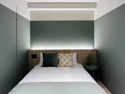 a bedroom with a bed with a green accent wall at HOTEL KANMA UENO in Tokyo