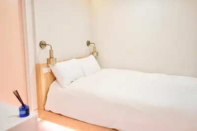 a white bed with two lamps on top of it at \u4e1c\u4eac\u4e0a\u91ce\u8d85\u7ea7\u4e2d\u5fc3 \u8bbe\u8ba1\u5e08\u623f\u95f4Yaoa \u4e0a\u91ce\u516c\u56ed3\u5206\u949f \u8f66\u7ad91\u5206\u949f \u8d85\u7ea7\u7e41\u534e \u514d\u8d39wifi \u6234\u68ee\u5439\u98ce in Tokyo