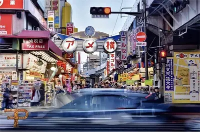 a car driving down a street in a city at \u4e1c\u4eac\u4e0a\u91ce\u8d85\u7ea7\u4e2d\u5fc3 \u8bbe\u8ba1\u5e08\u623f\u95f4Yaoa \u4e0a\u91ce\u516c\u56ed3\u5206\u949f \u8f66\u7ad91\u5206\u949f \u8d85\u7ea7\u7e41\u534e \u514d\u8d39wifi \u6234\u68ee\u5439\u98ce in Tokyo