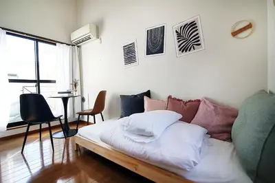 a living room with a bed with pillows on it at SUNRISE in Tokyo
