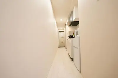 a corridor of a kitchen with white appliances at FL Residence Shinjuku II in Tokyo