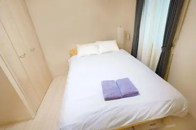 a small bedroom with a white bed with two towels on it at FL Residence Shinjuku II in Tokyo