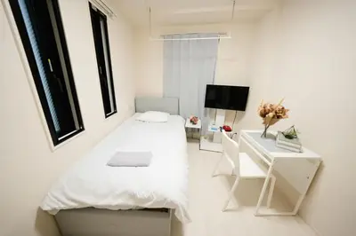 a small white bedroom with a bed and a desk at FL Residence Shinjuku II in Tokyo