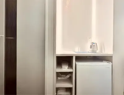 a kitchen with a white counter and a refrigerator at \u4e1c\u4eac\u4e0a\u91ce\u8d85\u7ea7\u4e2d\u5fc3 \u8bbe\u8ba1\u5e08\u623f\u95f4Ybob \u4e0a\u91ce\u516c\u56ed3\u5206\u949f \u8f66\u7ad91\u5206\u949f \u8d85\u7ea7\u7e41\u534e \u514d\u8d39wifi \u6234\u68ee\u5439\u98ce in Tokyo