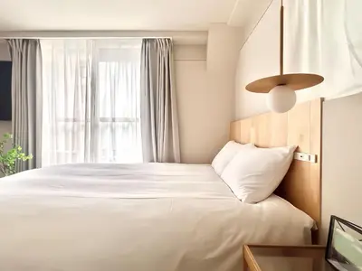 a bedroom with a white bed with a window at \u4e0a\u91ce\u8d85\u8c6a\u534e4\u4eba\u95f4 \u4e1c\u4eac\u8d85\u7ea7\u4e2d\u5fc3Ydoa \u8bbe\u8ba1\u5e08\u623f\u95f4 \u4e0a\u91ce\u516c\u56ed3\u5206\u949f \u8f66\u7ad91\u5206\u949f \u8d85\u7ea7\u7e41\u534e \u514d\u8d39wifi \u6234\u68ee\u5439\u98ce in Tokyo