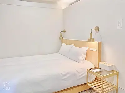 a bedroom with a white bed and a night stand at \u4e1c\u4eac\u4e0a\u91ce\u8d85\u7ea7\u4e2d\u5fc3 \u8bbe\u8ba1\u5e08\u623f\u95f4Yboe \u4e0a\u91ce\u516c\u56ed3\u5206\u949f \u8f66\u7ad91\u5206\u949f \u8d85\u7ea7\u7e41\u534e \u514d\u8d39wifi \u6234\u68ee\u5439\u98ce in Tokyo