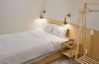 a bedroom with a white bed and a night stand at \u4e1c\u4eac\u4e0a\u91ce\u8d85\u7ea7\u4e2d\u5fc3 \u8bbe\u8ba1\u5e08\u623f\u95f4Yboe \u4e0a\u91ce\u516c\u56ed3\u5206\u949f \u8f66\u7ad91\u5206\u949f \u8d85\u7ea7\u7e41\u534e \u514d\u8d39wifi \u6234\u68ee\u5439\u98ce in Tokyo