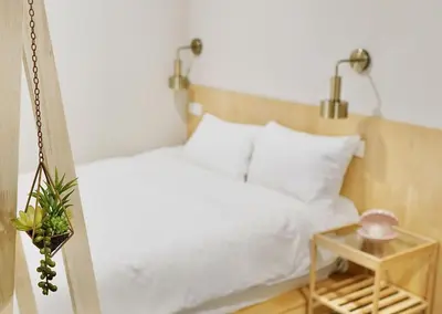 a bedroom with a white bed and a side table at \u4e1c\u4eac\u4e0a\u91ce\u8d85\u7ea7\u4e2d\u5fc3 \u8bbe\u8ba1\u5e08\u623f\u95f4Yboe \u4e0a\u91ce\u516c\u56ed3\u5206\u949f \u8f66\u7ad91\u5206\u949f \u8d85\u7ea7\u7e41\u534e \u514d\u8d39wifi \u6234\u68ee\u5439\u98ce in Tokyo